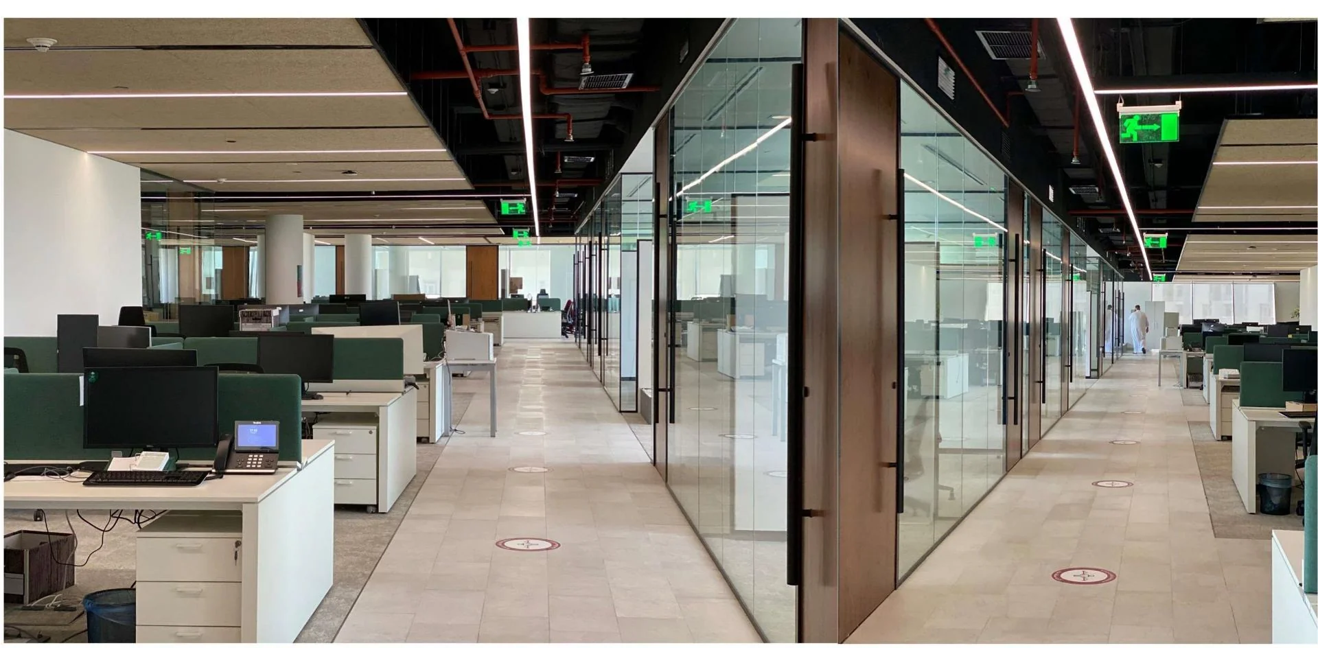 Open desks and a glazed meeting space beneath an exposed ceiling.